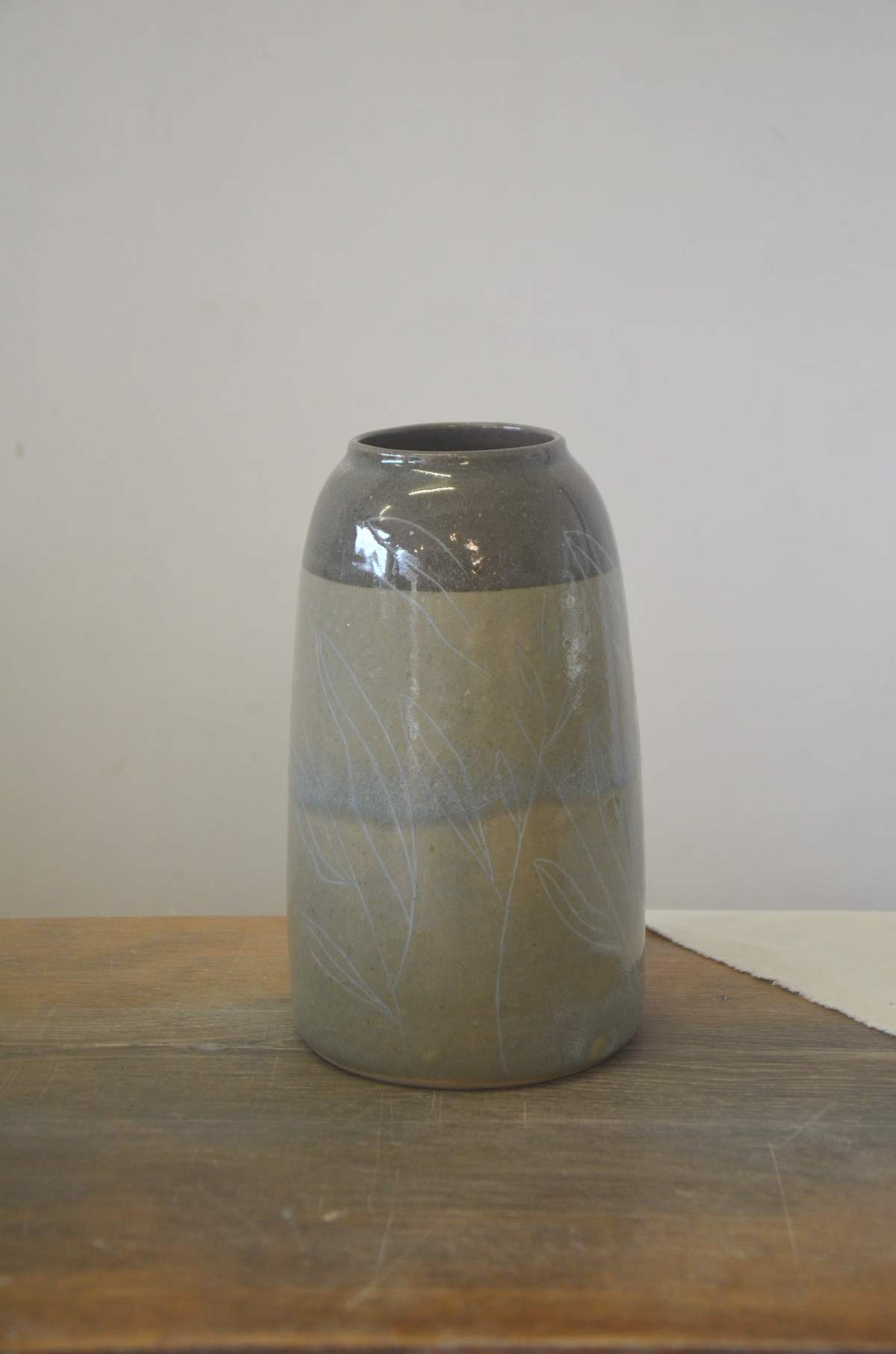 Vase gris-bleu à col foncé, décor de feuillages clairs.
