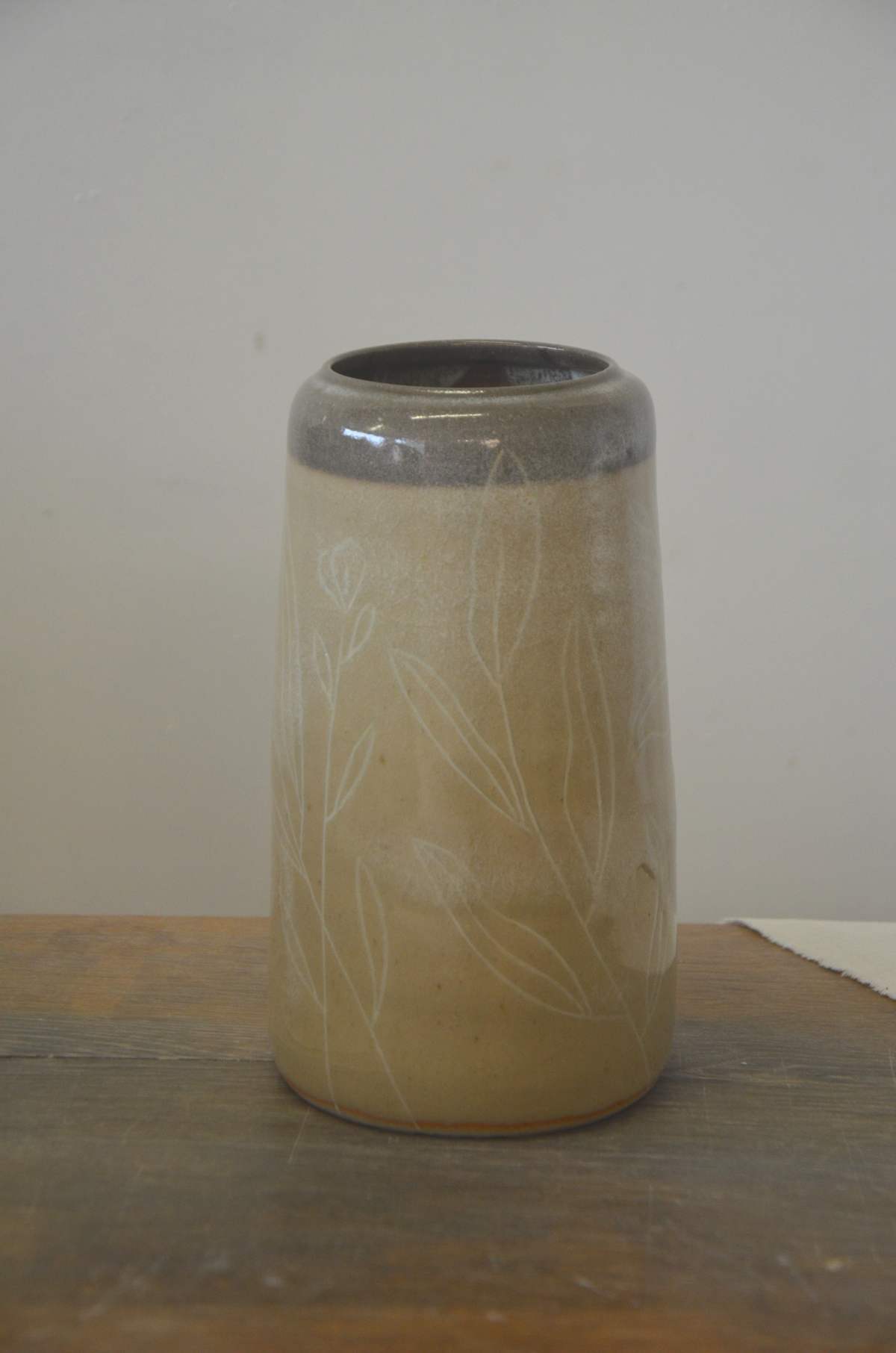 Vase beige à col gris, décor de feuillages blancs.