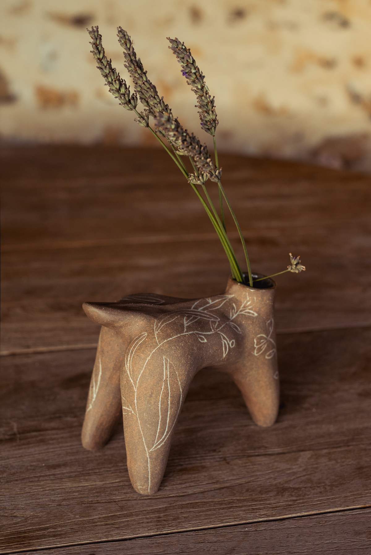 La même pièce brune à quatre pieds vue de profil, sur une table en bois clair.